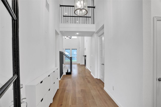 545 Oakmoss St, Little Elm, TX 76227 - hallway featuring light wood-style floors, a chandelier, a towering ceiling, and stairway