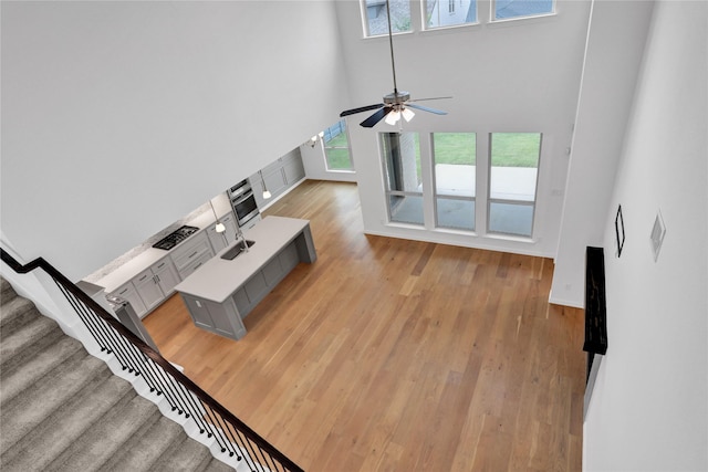 545 Oakmoss St, Little Elm, TX 76227 - unfurnished living room featuring healthy amount of natural light, a towering ceiling, light wood-style floors, stairs, and ceiling fan