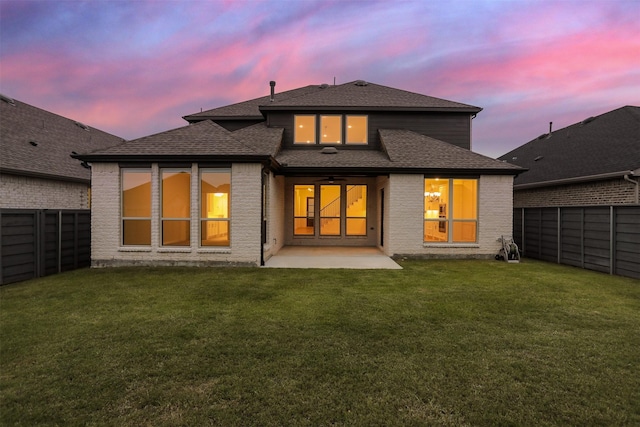 545 Oakmoss St, Little Elm, TX 76227 - back of house at dusk with a fenced backyard, a patio area, a shingled roof, and brick siding