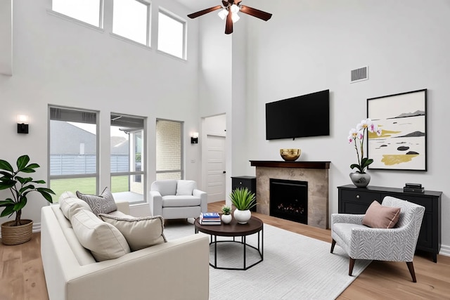 545 Oakmoss St, Little Elm, TX 76227 - living room featuring a high ceiling, ceiling fan, light wood finished floors, and a premium fireplace