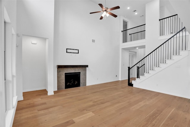 545 Oakmoss St, Little Elm, TX 76227 - unfurnished living room featuring a high ceiling, ceiling fan, stairway, a fireplace, and wood finished floors