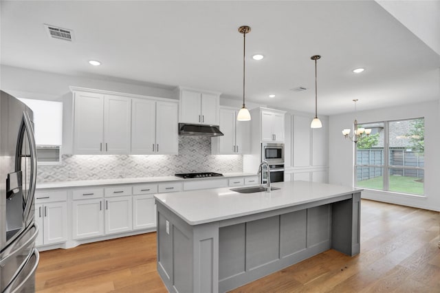 545 Oakmoss St, Little Elm, TX 76227 - kitchen with appliances with stainless steel finishes, under cabinet range hood, backsplash, light countertops, and white cabinets