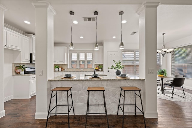 1021 Tara Dr, Burleson, TX 76028 - kitchen featuring a breakfast bar, decorative backsplash, white cabinetry, stainless steel microwave, and light stone countertops