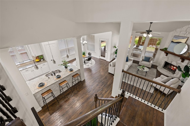 1021 Tara Dr, Burleson, TX 76028 - stairs with high vaulted ceiling, wood finished floors, a stone fireplace, a ceiling fan, and a chandelier