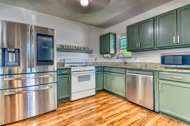 517 Pleasant Oaks Dr, Dallas, TX 75217 - kitchen with green cabinets, appliances with stainless steel finishes, light wood-type flooring, and light stone counters