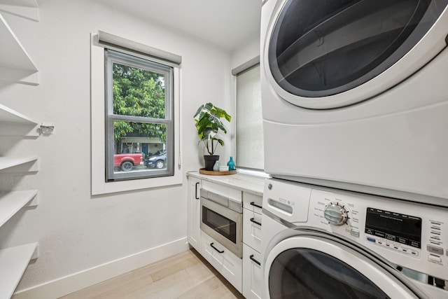 1921 Washington Ave, Fort Worth, TX 76110 - laundry area featuring stacked washer / drying machine, light wood finished floors, and cabinet space