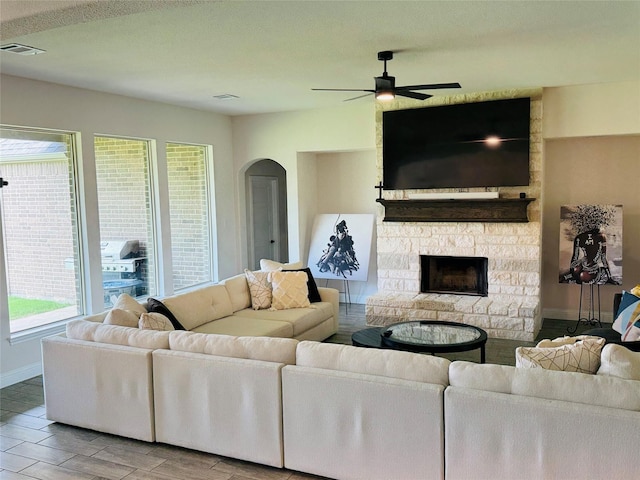 701 Winecup Way, Midlothian, TX 76065 - living room with a ceiling fan, a fireplace, wood finished floors, baseboards, and arched walkways