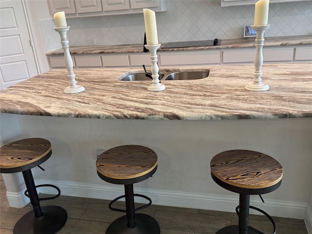 701 Winecup Way, Midlothian, TX 76065 - kitchen view of white cabinetry, a kitchen bar, baseboards, and backsplash