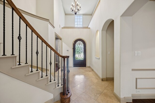 2610 Stonybrook Dr, Prosper, TX 75078 - tiled foyer with a chandelier, baseboards, arched walkways, stairway, and a towering ceiling