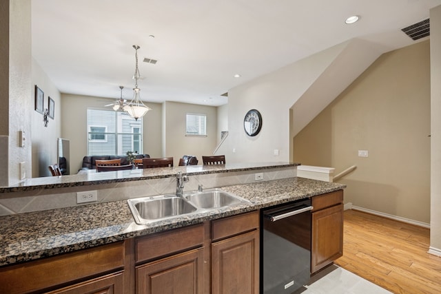 4121 Mckinney Ave Unit 21, Dallas, TX 75204 - kitchen featuring dishwashing machine, light wood finished floors, brown cabinetry, hanging light fixtures, and dark stone countertops