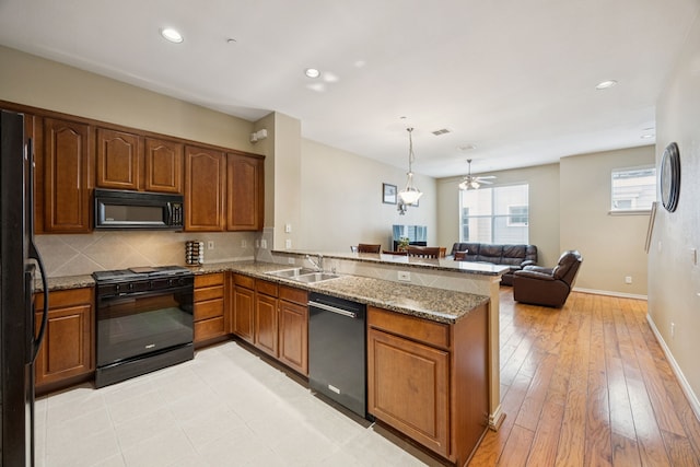 4121 Mckinney Ave Unit 21, Dallas, TX 75204 - kitchen featuring black appliances, stone counters, a peninsula, backsplash, and recessed lighting