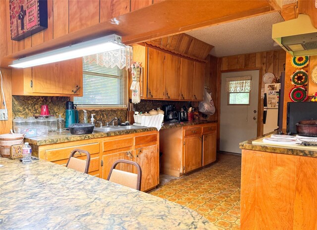 904 W 12th St, Cisco, TX 76437 - kitchen with range hood, tasteful backsplash, brown cabinets, and wood walls