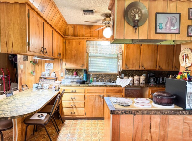904 W 12th St, Cisco, TX 76437 - kitchen featuring ceiling fan, a textured ceiling, a peninsula, wooden walls, and white electric cooktop