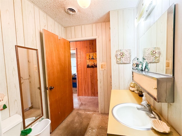 904 W 12th St, Cisco, TX 76437 - full bathroom featuring wooden walls, unfinished concrete flooring, a stall shower, vanity, and a textured ceiling