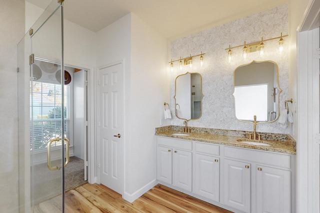 1225 Long Leaf Dr, Savannah, TX 76227 - bathroom featuring wood finished floors, double vanity, wallpapered walls, and a shower with shower door