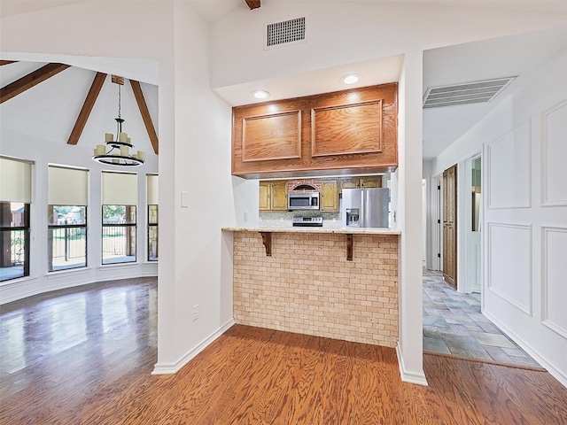 9101 Westwood Shores Dr, Fort Worth, TX 76179 - kitchen featuring stainless steel appliances, light countertops, wood finished floors, a breakfast bar, and beamed ceiling