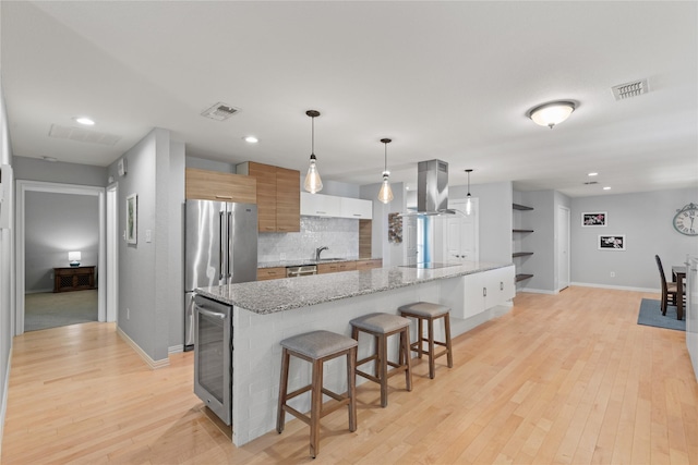 5963 River Bend Dr, Benbrook, TX 76132 - kitchen featuring island exhaust hood, stainless steel appliances, wine cooler, backsplash, and a kitchen breakfast bar