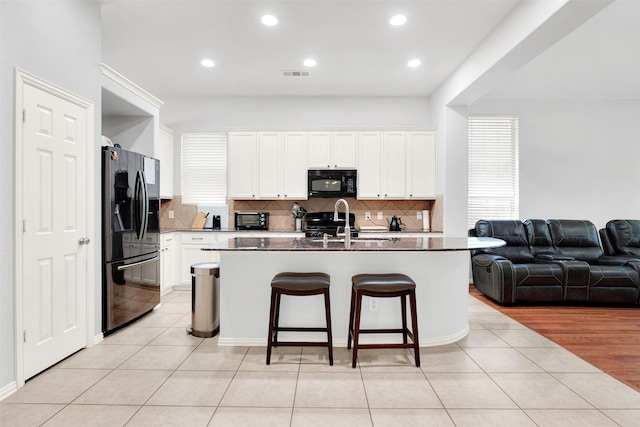 1505 Pelican Dr, Little Elm, TX 75068 - kitchen featuring stainless steel fridge, black microwave, open floor plan, light tile patterned floors, and recessed lighting