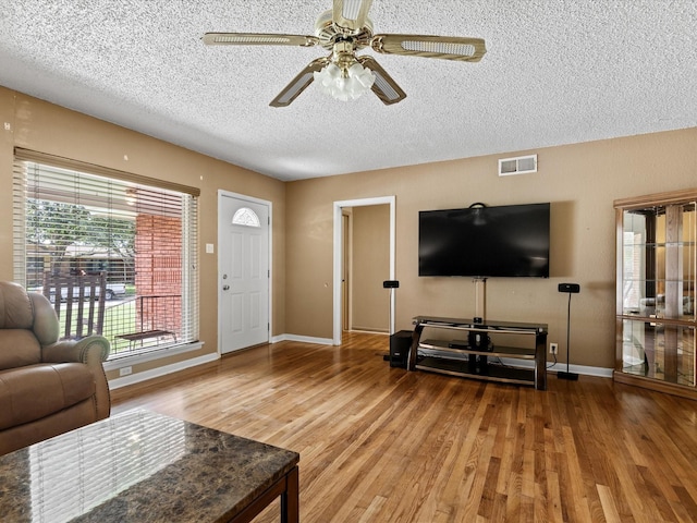 301 Redbud, Ferris, TX 75125 - living area with wood finished floors, ceiling fan, and a textured ceiling
