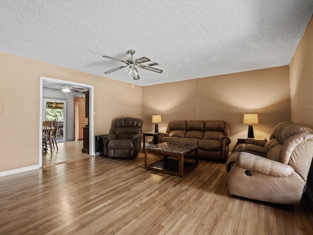 301 Redbud, Ferris, TX 75125 - living room with a textured ceiling, light wood-type flooring, and a ceiling fan
