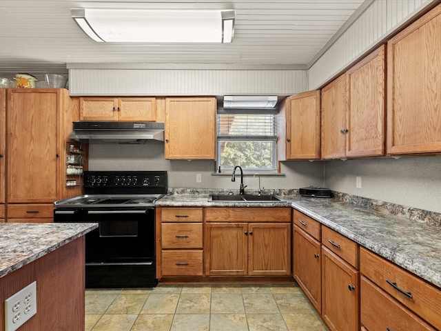 301 Redbud, Ferris, TX 75125 - kitchen with black / electric stove, under cabinet range hood, light stone countertops, and brown cabinetry