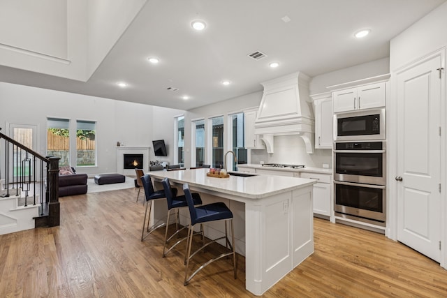 3623 Coldstream Dr, Irving, TX 75063 - kitchen featuring double oven, black microwave, a center island with sink, a kitchen breakfast bar, and a lit fireplace