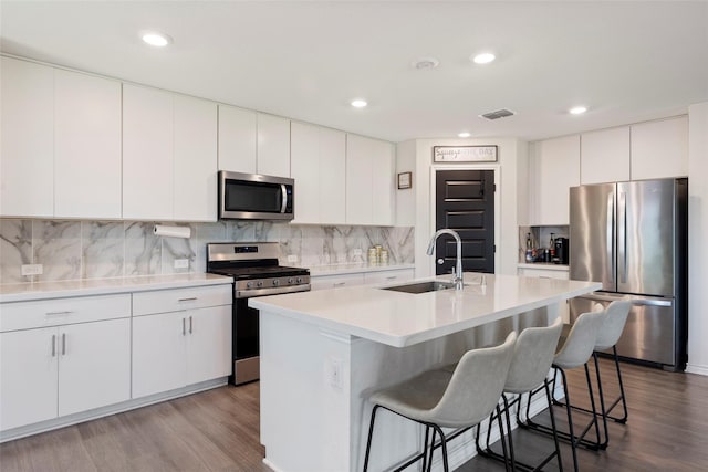 816 Adair Dr, Aubrey, TX 76227 - kitchen featuring appliances with stainless steel finishes, wood finished floors, a breakfast bar area, backsplash, and recessed lighting