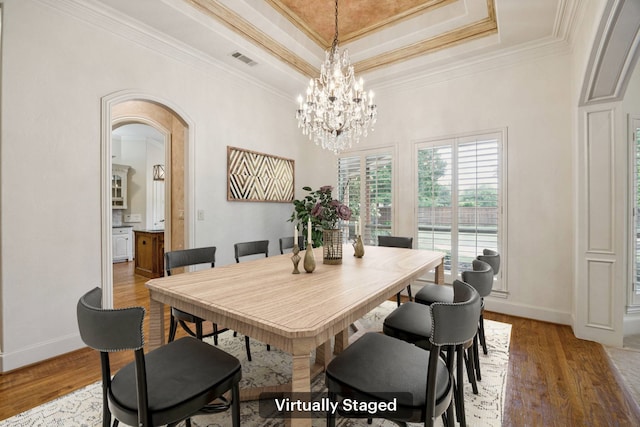 205 Suncreek Dr, Allen, TX 75013 - dining area with a raised ceiling, ornamental molding, light wood-style flooring, a chandelier, and arched walkways