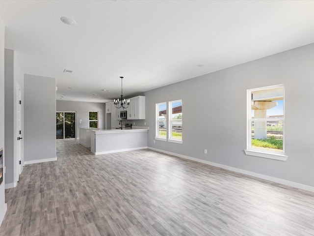 1609 E Bluff St, Fort Worth, TX 76102 - unfurnished living room featuring light wood-type flooring and a chandelier