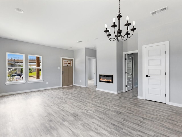 1609 E Bluff St, Fort Worth, TX 76102 - unfurnished living room featuring light wood finished floors, a chandelier, and a glass covered fireplace