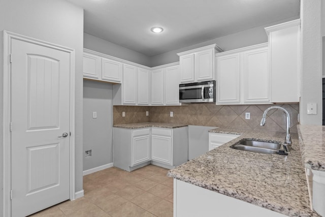 920 Fox Grove Ln, Providence Village, TX 76227 - kitchen with stainless steel microwave, light stone countertops, white cabinets, tasteful backsplash, and light tile patterned flooring