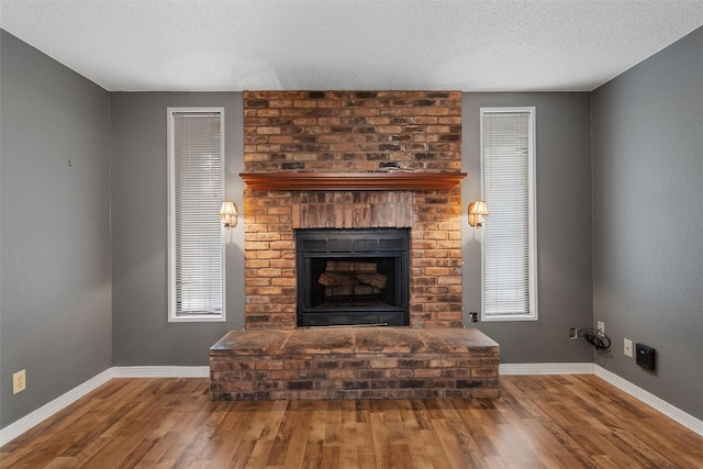 3808 Leland Ave, Waco, TX 76708 - living room featuring wood finished floors, a textured ceiling, and a brick fireplace