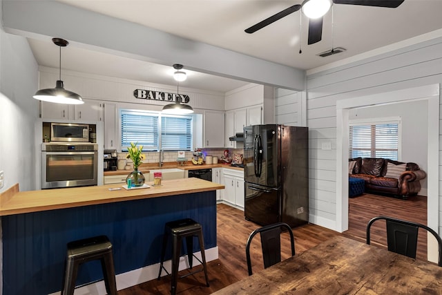 714 W Ball St, Weatherford, TX 76086 - kitchen with black appliances, ceiling fan, dark wood-style flooring, butcher block countertops, and a peninsula