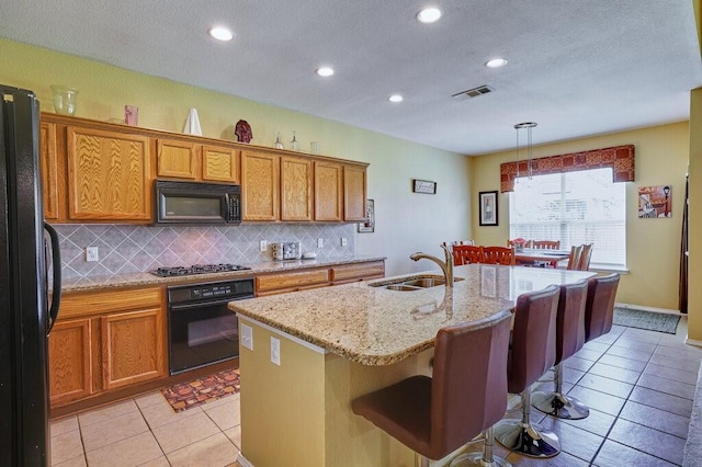1013 Lilac Ln, Desoto, TX 75115 - kitchen with black appliances, decorative backsplash, a kitchen island with sink, light tile patterned flooring, and recessed lighting