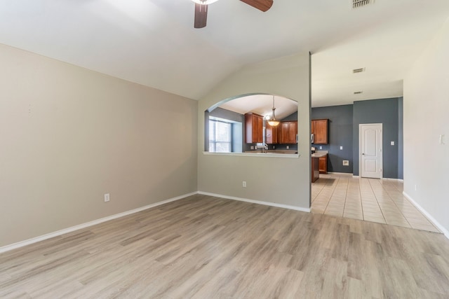 8128 Guadalupe Rd, Arlington, TX 76002 - unfurnished living room with ceiling fan, light wood-type flooring, arched walkways, and vaulted ceiling