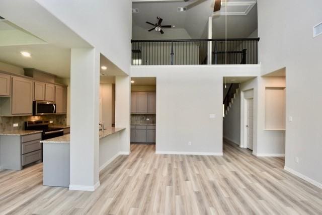 2605 Donella Dr, Denton, TX 76207 - unfurnished living room with ceiling fan, a towering ceiling, and light wood-style flooring
