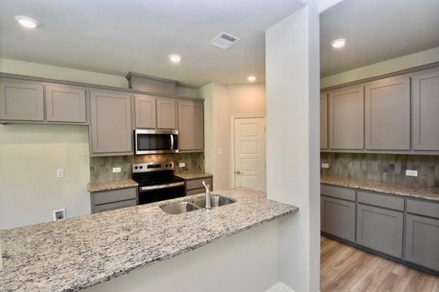 2605 Donella Dr, Denton, TX 76207 - kitchen featuring stainless steel appliances, gray cabinets, light stone counters, light wood-style flooring, and recessed lighting