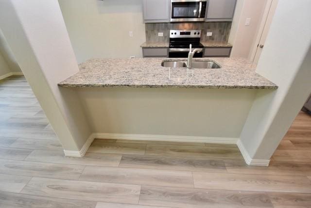 2605 Donella Dr, Denton, TX 76207 - kitchen with appliances with stainless steel finishes, wood finished floors, a peninsula, and light stone countertops