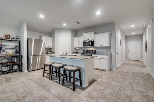 632 Peshtigo Rd, Justin, TX 76247 - kitchen featuring appliances with stainless steel finishes, white cabinetry, an island with sink, recessed lighting, and light stone counters