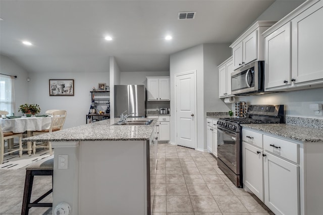 632 Peshtigo Rd, Justin, TX 76247 - kitchen featuring appliances with stainless steel finishes, a center island with sink, white cabinets, light stone countertops, and recessed lighting