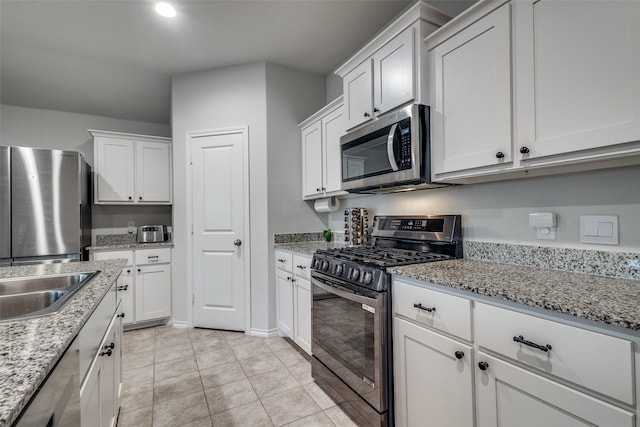 632 Peshtigo Rd, Justin, TX 76247 - kitchen featuring appliances with stainless steel finishes, white cabinets, light tile patterned flooring, and light stone countertops