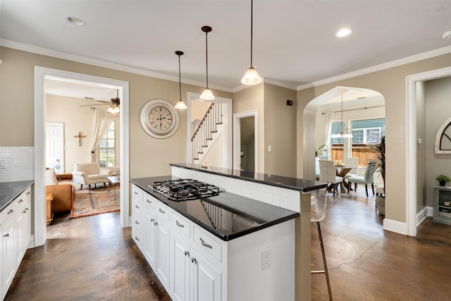 2309 Ryan Ave, Fort Worth, TX 76110 - kitchen featuring dark countertops, black gas cooktop, concrete flooring, arched walkways, and ornamental molding