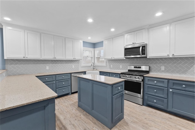 310 Lexington Ave, Abilene, TX 79605 - kitchen with appliances with stainless steel finishes, white cabinets, blue cabinets, light wood-style flooring, and decorative backsplash