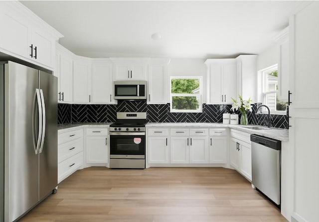 903 N Miller St, Decatur, TX 76234 - kitchen with stainless steel appliances, white cabinets, decorative backsplash, and light wood-type flooring