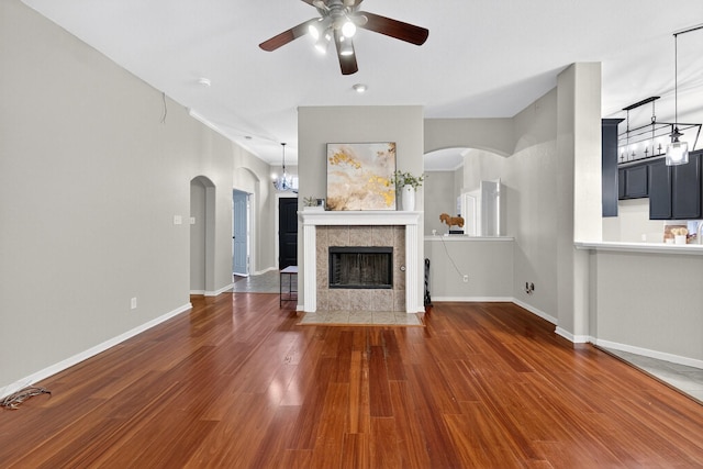 5537 Seabury Dr, Fort Worth, TX 76137 - unfurnished living room with ceiling fan, wood finished floors, arched walkways, a fireplace, and a chandelier
