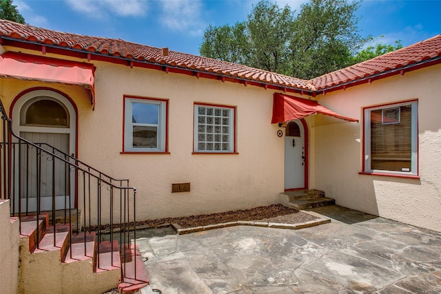 6812 Clayton Ave, Dallas, TX 75214 - doorway to property with a tile roof, stucco siding, and a patio area