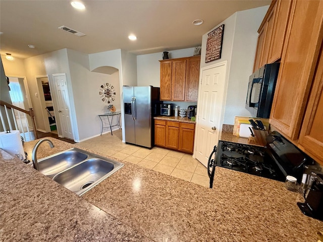 1117 Prairie Heights Dr, Fort Worth, TX 76108 - kitchen featuring black appliances, brown cabinets, light tile patterned floors, recessed lighting, and arched walkways
