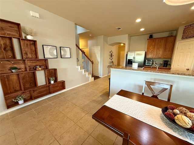 1117 Prairie Heights Dr, Fort Worth, TX 76108 - kitchen with stainless steel fridge, arched walkways, light tile patterned floors, recessed lighting, and light stone counters