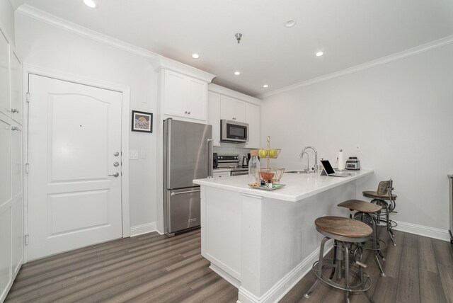 3400 Welborn St Unit 224, Dallas, TX 75219 - kitchen featuring stainless steel appliances, a breakfast bar area, dark wood-style flooring, crown molding, and a peninsula