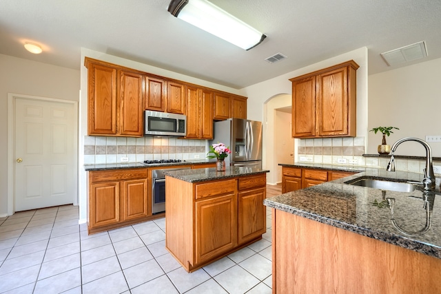 4424 Ridge Point Ln, Plano, TX 75024 - kitchen featuring appliances with stainless steel finishes, dark stone counters, tasteful backsplash, and brown cabinets